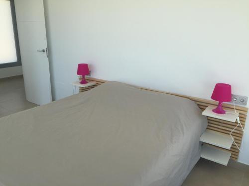 a bedroom with a bed with two lamps on books at 3018 Vistabella- Malibu in Orihuela