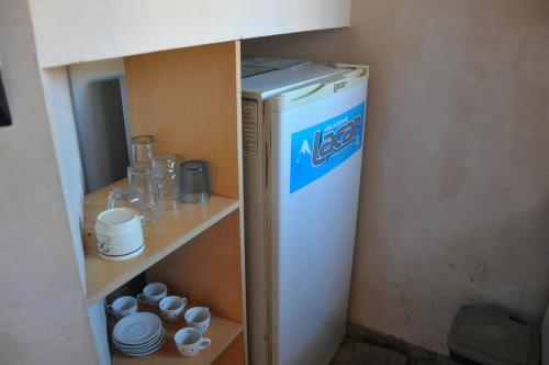 a small refrigerator in a room with cups and plates at Perick Termas in Colón
