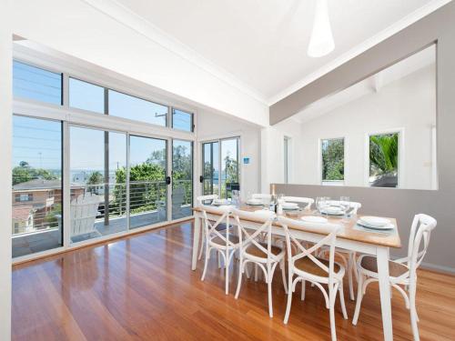 a white dining room with a table and chairs at Beachside Haven - Your Perfect Oasis Home in Nelson Bay