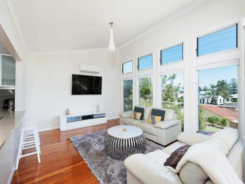 a living room with white furniture and large windows at Beachside Haven - Your Perfect Oasis Home in Nelson Bay