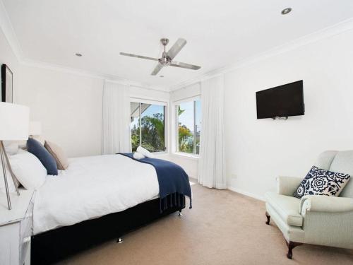 biała sypialnia z łóżkiem i krzesłem w obiekcie Beachside Haven - Your Perfect Oasis Home w mieście Nelson Bay