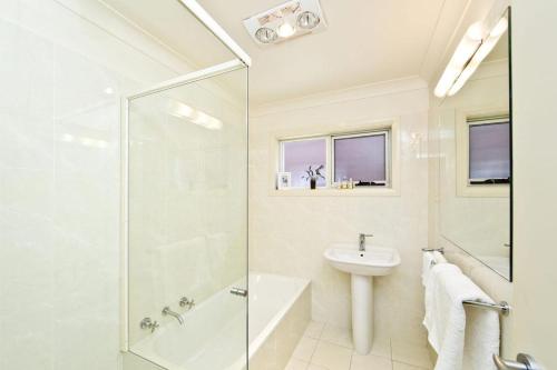 La salle de bains blanche est pourvue d'une douche et d'un lavabo. dans l'établissement Beachside Haven - Your Perfect Oasis Home, à Nelson Bay