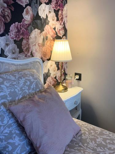 um quarto com uma cama com um candeeiro e um papel de parede florido em Anita 
