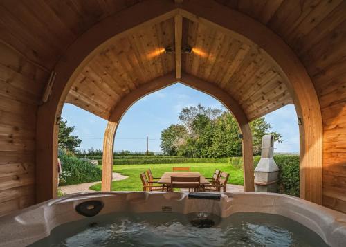uma banheira de hidromassagem exterior numa casa de madeira com um arco em Luckington Burrows em Frome