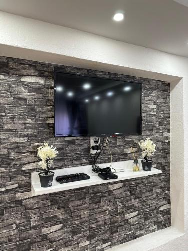 a tv on a wall with a stone wall at Hostel Gray in Kruševac