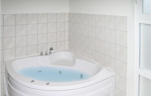 HaslevgårdeにあるAmazing Home In Hadsund With 3 Bedrooms, Sauna And Wifiの白いタイル張りのバスルーム(白いバスタブ付)
