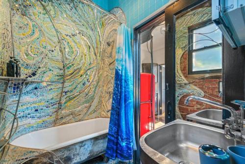 a bathroom with a tub and a mosaic wall at Artistic Loft A Century-Old Gem in Brooklyn