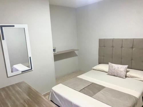 Dormitorio pequeño con cama y espejo en Hotel Bahia Suite, en Santa Marta