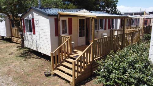 une petite maison avec un porche et une terrasse dans l'établissement AU 120 Grand mobilhome clim, à Port-la-Nouvelle