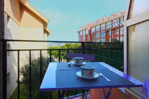 einem blauen Tisch mit zwei Tassen und einem Löffel auf dem Balkon in der Unterkunft Entre Playa y Puntal in Somo