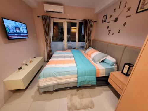 een slaapkamer met een bed, een bad en een televisie bij skyview apartemen by gowsleep in Sunggal