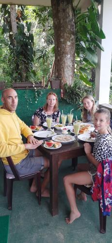 un grupo de personas sentadas alrededor de una mesa comiendo comida en New green leaf resort, en Ella