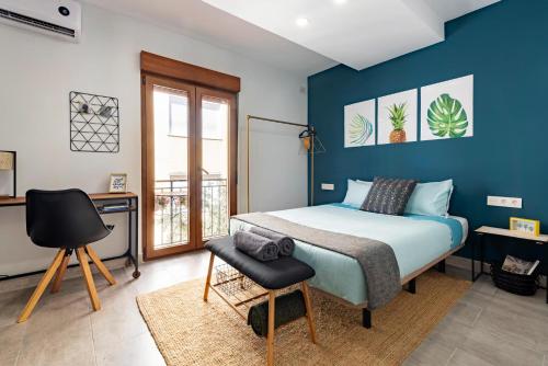 Schlafzimmer mit blauen Wänden, einem Bett und einem Stuhl in der Unterkunft Oleti Studio Granada in Granada