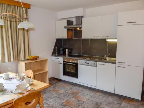 a kitchen with white cabinets and a wooden table at Apartment Schöngraben by Interhome in Sankt Jakob