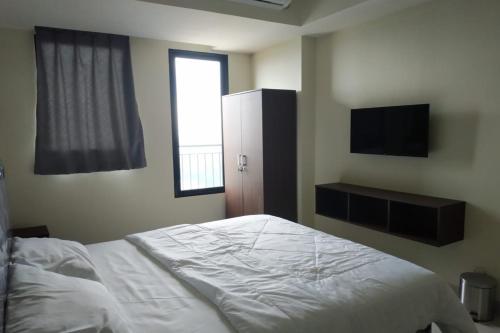 Schlafzimmer mit einem weißen Bett und einem TV in der Unterkunft OYO Life 92745 The Margo Monthly Stay in Depok