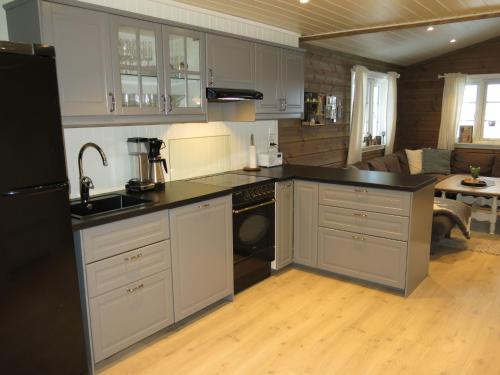 cocina con armarios blancos y nevera negra en Chalet Fjellkos - SOW146 by Interhome en Fossdal