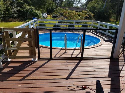 a wooden deck with a pool and a fence at Holiday Home Asmine - 670m from the sea in Lolland- Falster and Mon by Interhome in Dannemare