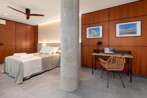 a bedroom with a bed and a desk with a laptop at Calatrava by Alma Suites in Valencia