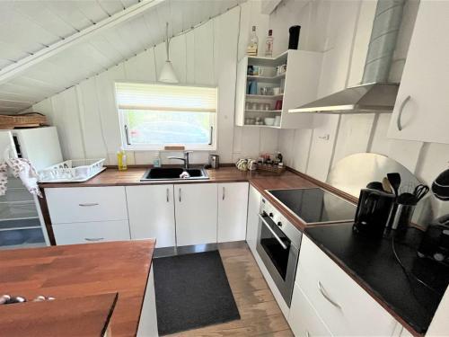 eine Küche mit weißen Schränken und schwarzen Arbeitsplatten in der Unterkunft Holiday Home Ninni - 3-2km from the sea in Sealand by Interhome in Eskebjerg