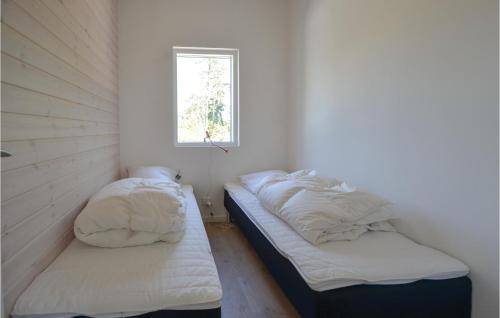 two beds in a small room with a window at Amazing Home In Ebeltoft With 3 Bedrooms, Sauna And Wifi in Ebeltoft