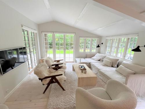 ein Wohnzimmer mit einem weißen Sofa und Stühlen in der Unterkunft Holiday Home Torben - 750m from the sea in Sealand by Interhome in Nykøbing Sjælland