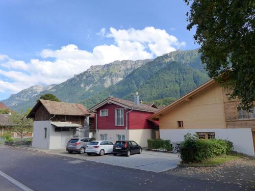 a group of houses and cars parked in front of a mountain at Apartment Tilia by Interhome in Bönigen