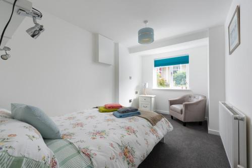 a bedroom with a bed and a chair and a window at Seaweed in Combe Martin