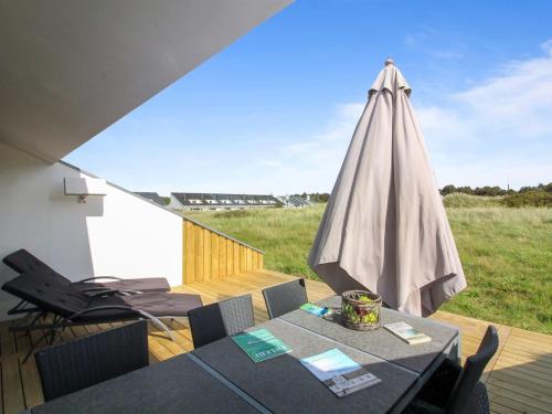 eine Terrasse mit einem Tisch und einem Sonnenschirm in der Unterkunft Apartment Virpi - 1km from the sea in NW Jutland by Interhome in Blokhus