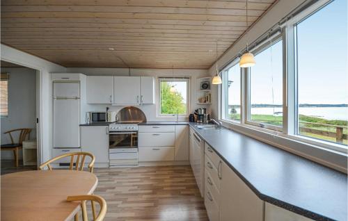 エーベルトフトにあるStunning Home In Ebeltoft With 2 Bedrooms And Wifiの白いキャビネットとテーブル付きのキッチン、一部の窓