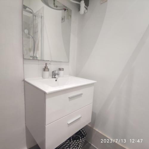 une salle de bain blanche avec un lavabo et un miroir dans l'établissement Appartement quai de Joliette/ mucem/major, à Marseille