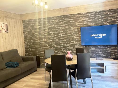 a living room with a table and a tv on a wall at Vall d'Incles TOP NATURE, A13, HUT 5836 in Canillo