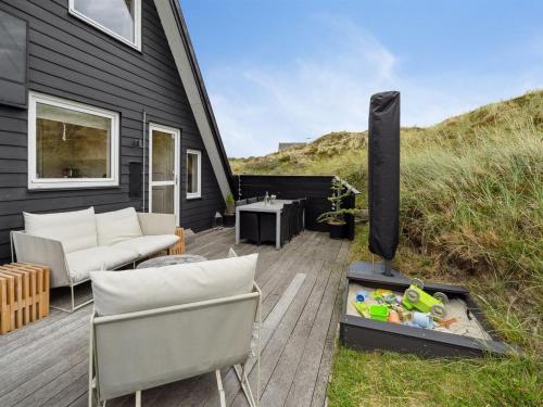 een patio met een open haard en een bank en stoelen bij Holiday Home Pauli - 350m from the sea in NW Jutland by Interhome in Pandrup