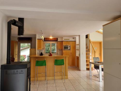 cocina con encimera y 2 taburetes verdes en Holiday Home Le Chant de la Dranse by Interhome, en Sembrancher