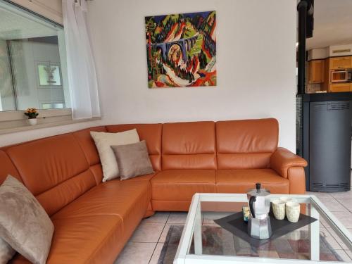 un sofá naranja en una sala de estar con mesa en Holiday Home Le Chant de la Dranse by Interhome, en Sembrancher