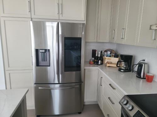 a stainless steel refrigerator in a kitchen with white cabinets at Good Fortune Residence, Ottawa in Ottawa