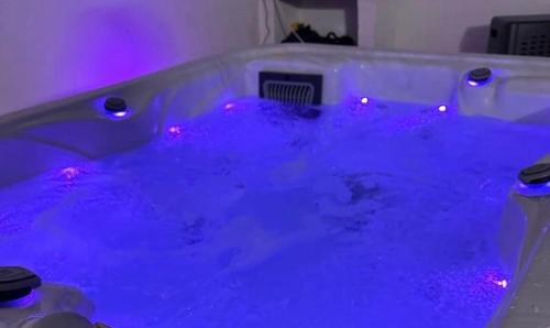 una vasca da bagno blu con luci viola in camera di Qatar Apartment a Cosenza