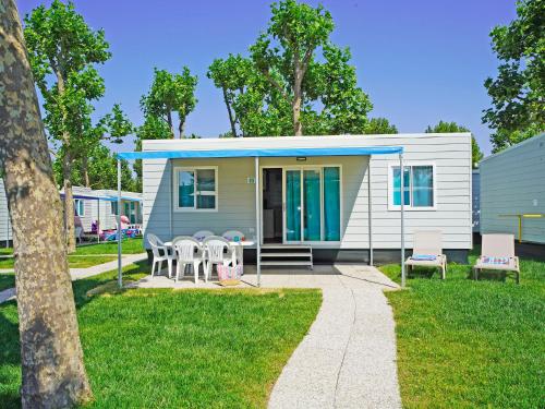 a tiny house with a patio and chairs at Holiday Home San Francesco Camping Village by Interhome in Rivoltella