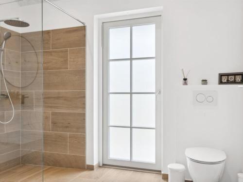 ein Badezimmer mit Dusche, Toilette und Fenster in der Unterkunft Holiday Home Bryngeir - 750m from the sea by Interhome in Brøndstrup