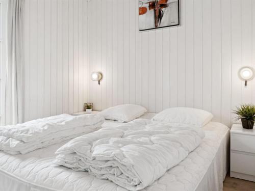ein großes weißes Bett in einem weißen Zimmer in der Unterkunft Holiday Home Bryngeir - 750m from the sea by Interhome in Brøndstrup
