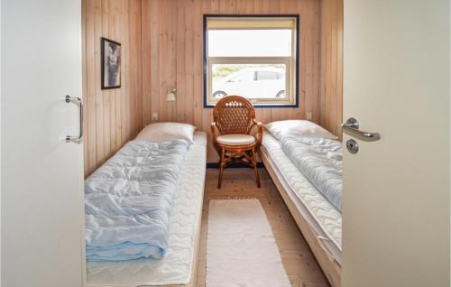 Habitación con 2 camas y una silla. en Nice Home In Hjrring With 4 Bedrooms, Sauna And Wifi, en Kærsgård Strand