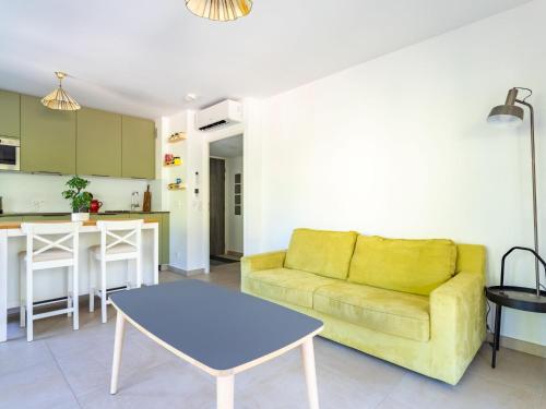 un salon avec un canapé jaune et une table dans l'établissement Apartment Le Clos Jardin-4 by Interhome, à Bormes-les-Mimosas