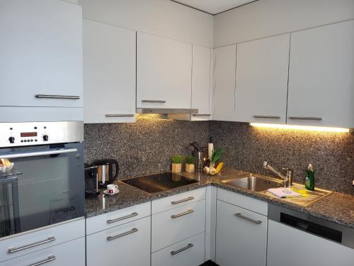 a kitchen with white cabinets and a sink at Apartment Torre Tessuti Apt-Stefano by Interhome in Locarno
