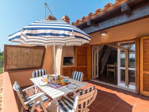 Una mesa y sillas con una sombrilla en un patio. en Apartment Arcobaleno by Interhome, en Porto Istana