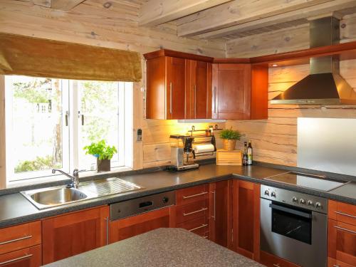 een keuken met houten kasten en een wastafel bij Chalet Xenia - TEM204 by Interhome in Vradal