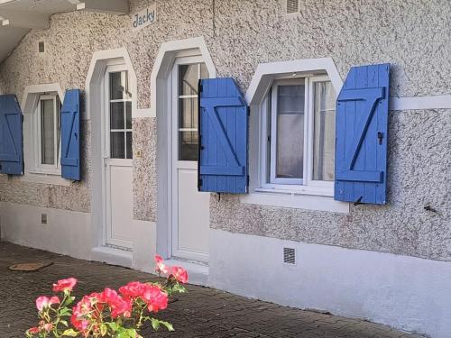 a building with blue shutters and flowers in front of it at Apartment Jacky by Interhome in Le Pouliguen