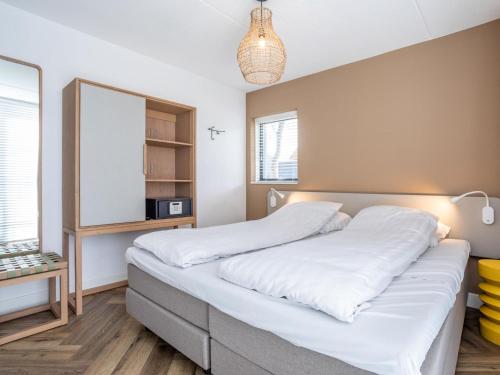 a bedroom with a large bed and a mirror at Holiday Home Putter Comfort by Interhome in Noordwijk