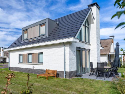 a white house with a black roof at Holiday Home Putter Comfort by Interhome in Noordwijk