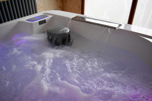 bañera llena de agua púrpura con cepillo en Casa Rural Puente Moneo, en Garcibuey
