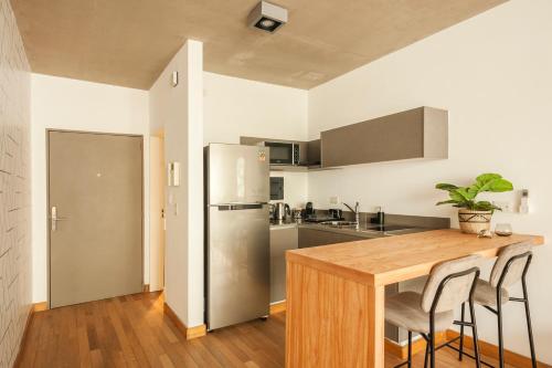 cocina con mesa de madera y nevera de acero inoxidable en Viví Buenos Aires en este Studio de Diseño #202 en Buenos Aires