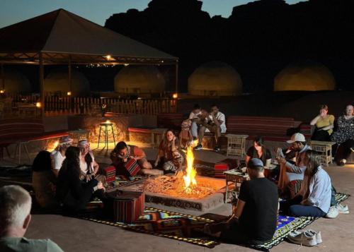 Un gruppo di persone seduti intorno a un focolare di Wadi Rum living camp a Wadi Rum
